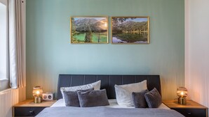 Une chambre à coucher avec un lit, deux lampes de chevet, une tête de lit et deux tableaux encadrés accrochés au mur.