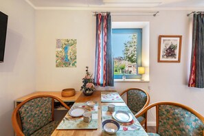 Een eetgedeelte met een tafel voor vier personen, stoelen, een kaart aan de muur en een raam met gordijnen.
