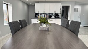 Un salón de conferencias con una mesa grande, sillas negras, una planta en maceta y armarios blancos al fondo.