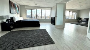 Una habitación de hotel moderna con una cama grande, un escritorio, una silla, un sofá y un amplio ventanal con vistas a la ciudad.