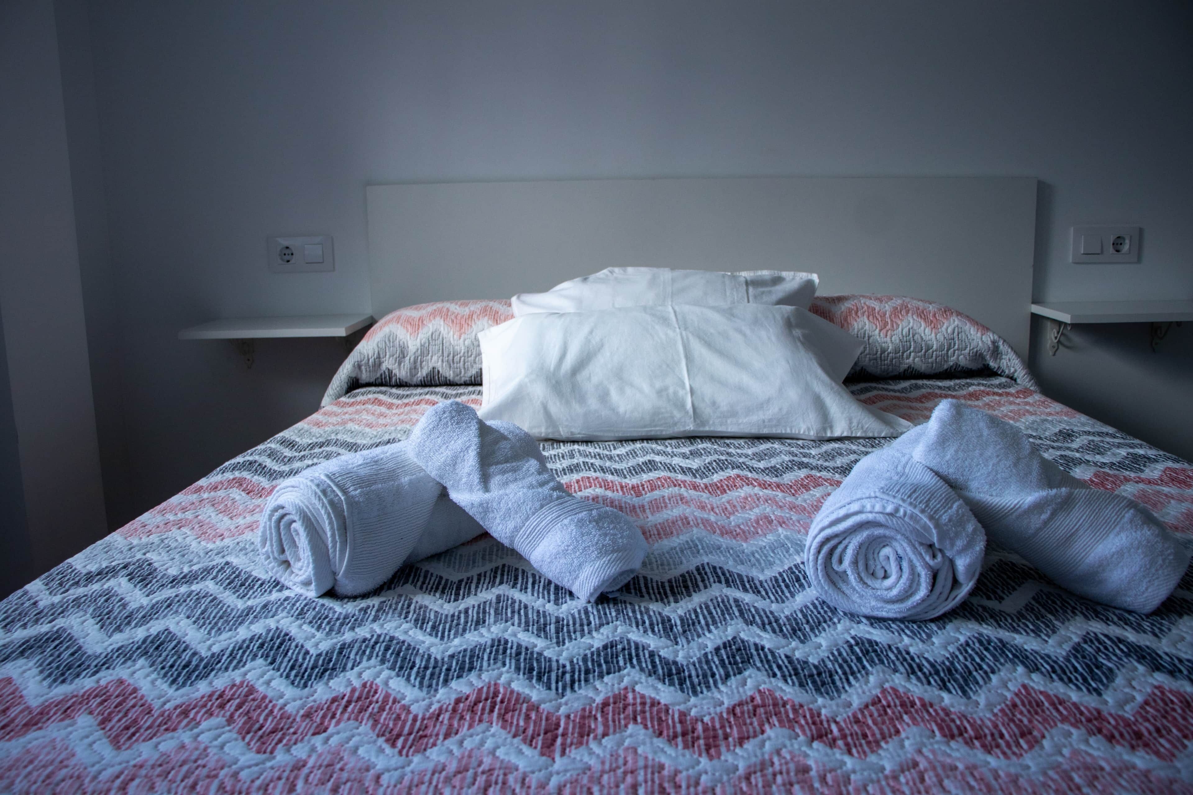 Un lit bien fait, avec une couvre-lit à motifs, des oreillers et des serviettes enroulées.