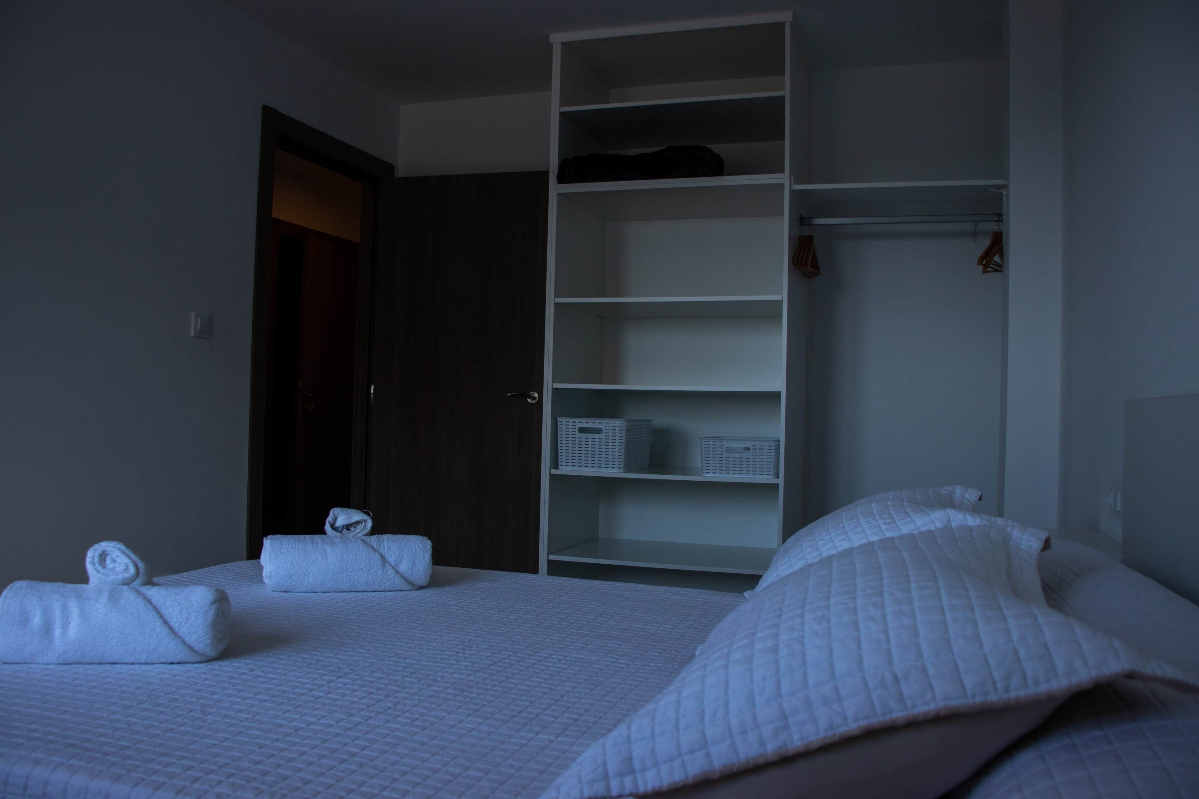 Una habitación de hotel con cama, armario y puerta.