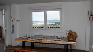 A dining table with a view of a bridge and hills, a bench, and a potted plant.