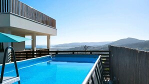 A rooftop pool with a clear view of the sea and mountains.
