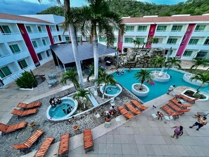 A hotel with multiple swimming pools, lounge areas, and a mountainous backdrop. - HOTEL LA ISLA HUATULCO H (Santa María Huatulco)