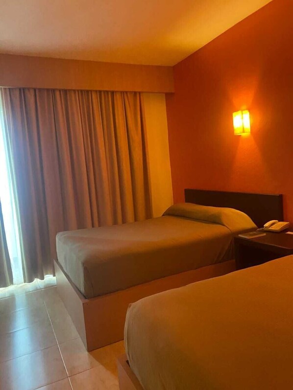 A hotel room with two beds, a nightstand with a phone, and a window with curtains. - HOTEL LA ISLA HUATULCO H (Santa María Huatulco)