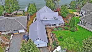 A large house with a steeply pitched roof, a stone foundation, and a well-maintained lawn. - Lakefront Cottage w/Hot Tub, BBQ Grill, Deck, Fire Pit, Fire Place, Sauna, Dock. (Beaverton)