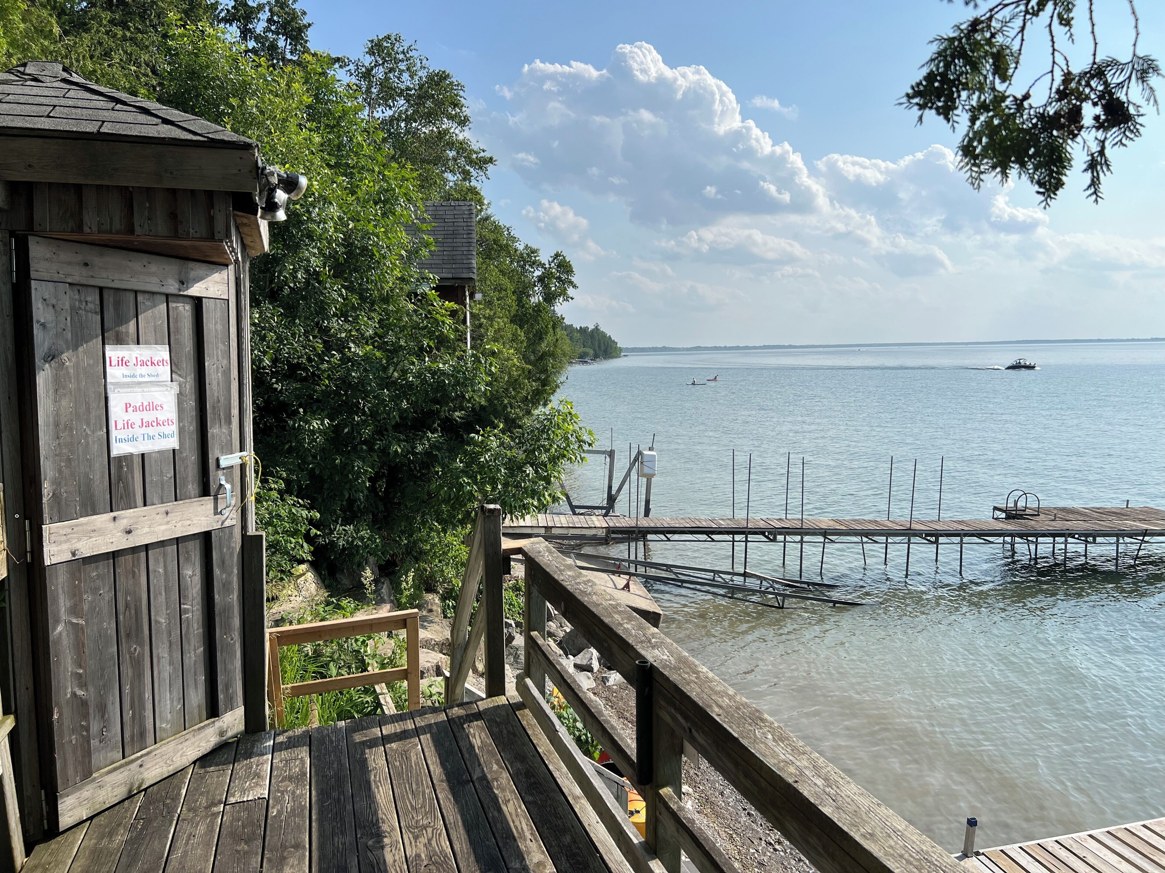 A wooden dock leading to a body of water with a boat in the distance.