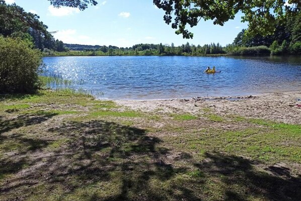 A calm lake with a kayak on the water, surrounded by greenery and trees. - Vakantiehuis, Sauna, Jacuzzi, Airconditioning (gmina Sianów)