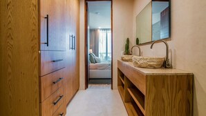 Ein modernes Badezimmer mit Holzschränken, einem großen Spiegel und einem Becken aus Stein.