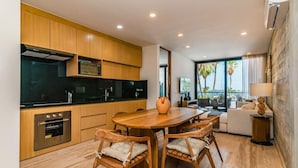 Eine moderne Küche mit Holzschränken, einer schwarzen Arbeitsplatte und einem eingebauten Backofen. Es gibt einen Essbereich mit einem Holztisch und Stühlen.