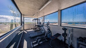 Ein Fitnessstudio mit Trainingsgeräten, großen Fenstern und Blick ins Freie.