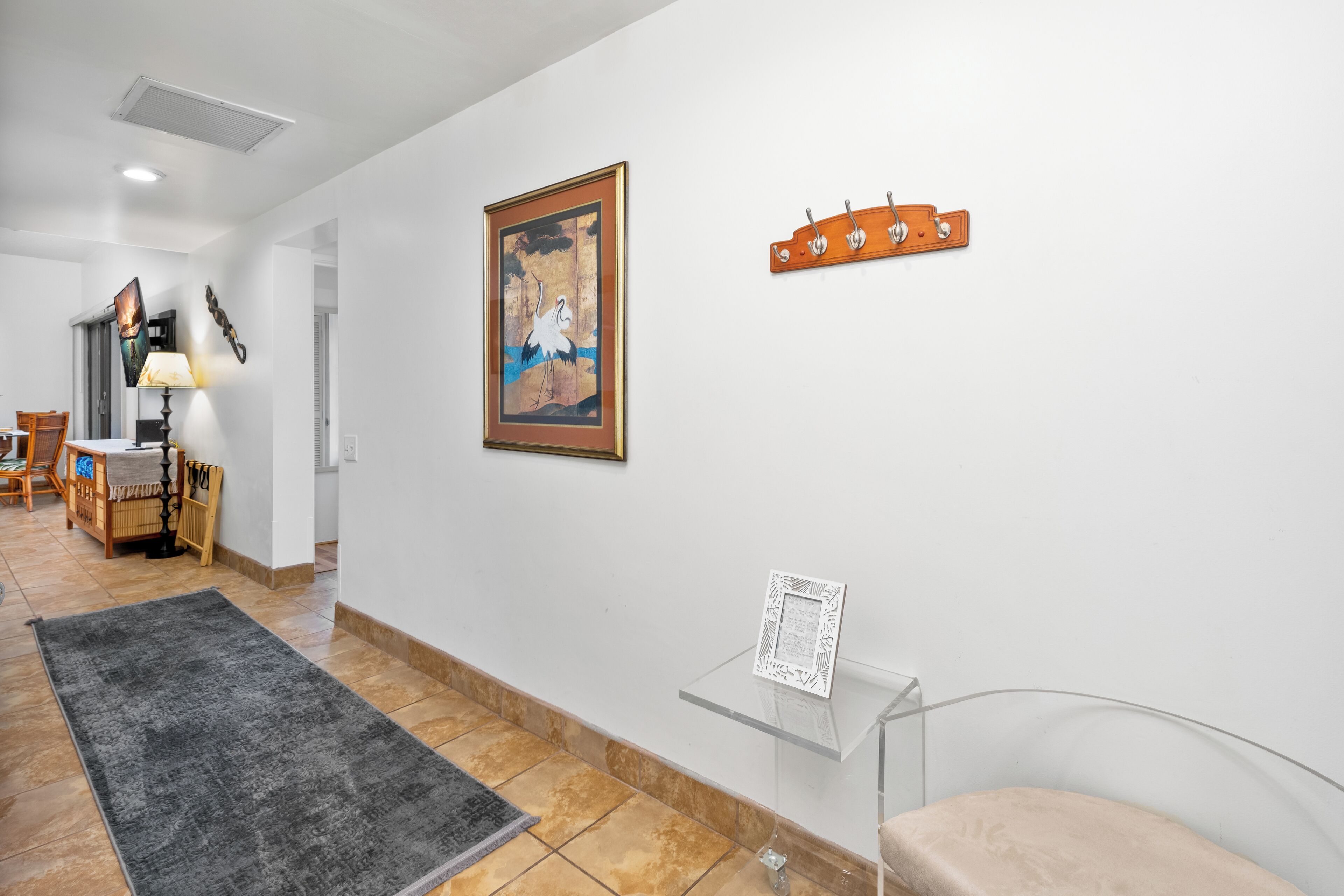 A hallway with a framed artwork, a coat rack, and a glass display case.