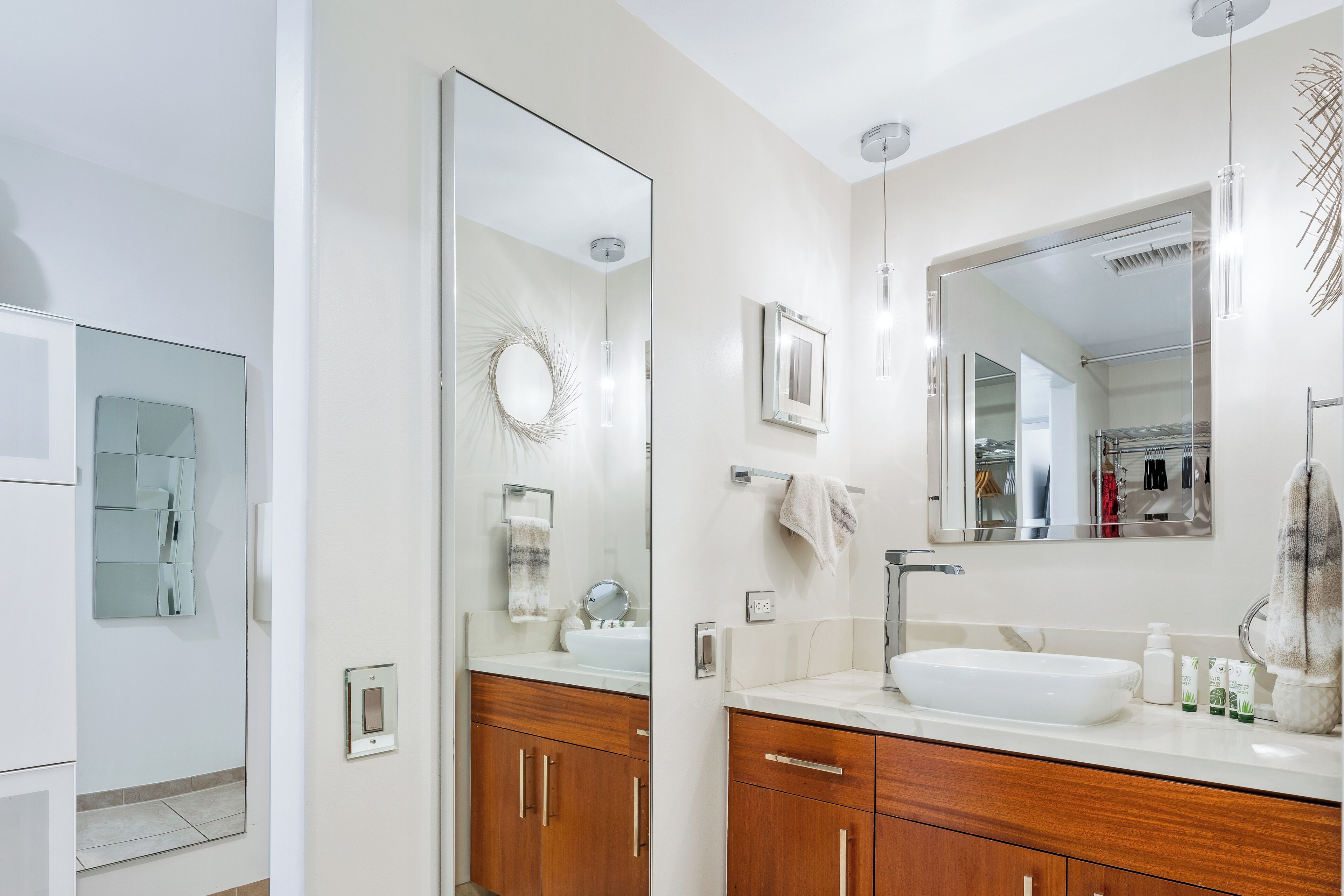 Een moderne badkamer met een grote spiegel, een wastafel, houten kastjes en een handdoekrek.