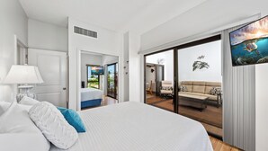Ein modernes Hotelzimmer mit einem großen Bett, einem Fernseher und einer Schiebetür zu einem Balkon mit einer Sitzecke und Blick ins Freie.