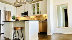 A modern kitchen with white cabinets, stainless steel appliances, and a herringbone patterned backsplash. - Charming 1-bedroom apartment with views (Dallas)