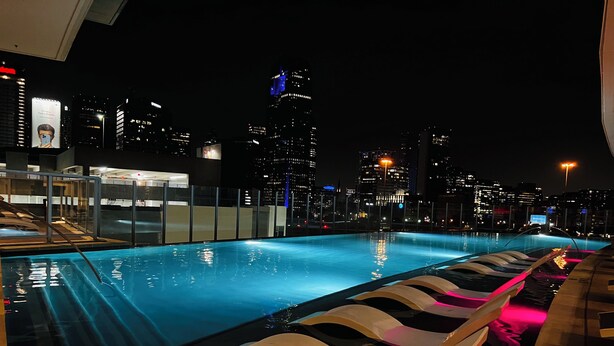 A nighttime view of a rooftop pool with city skyline in the background. - Charming 1-bedroom apartment with views (Dallas)