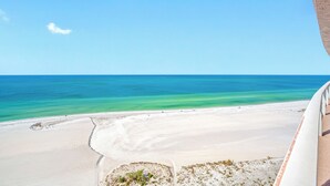 Une plage à l’eau turquoise et au sable blanc, vue depuis un espace abrité.
