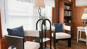 Une pièce chaleureuse avec deux fauteuils, une bibliothèque et une petite table.