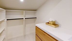 A clean, modern bathroom with white walls, a wooden vanity, and a towel rack. - JHRL - Hollyhock 2023 (Wilson)