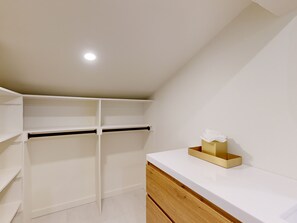Relax in a cozy loft-style room with a sloped ceiling, featuring a recessed light fixture, a black accent wall, and a convenient countertop with a cabinet.