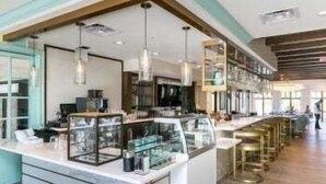 A modern interior with a central counter, glass display cases, hanging pendant lights, and a bar area. - Orlando Oasis: Themed Rooms, Pool & Surf Simulator (Kissimmee)