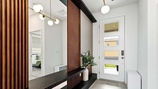 A modern hallway with a black marble bench, a wooden slat wall, and a white door with multiple windows. - Orlando Oasis: Themed Rooms, Pool & Surf Simulator (Kissimmee)