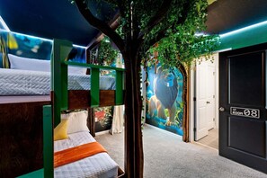 Una habitación con literas, un mural de un león y una puerta con la inscripción 'ROOM 08'.
