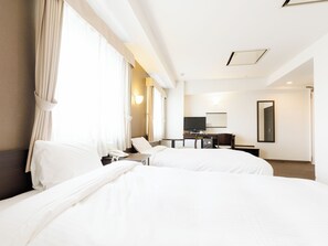 Habitación de hotel con dos camas, un escritorio, televisión, teléfono y espejo.