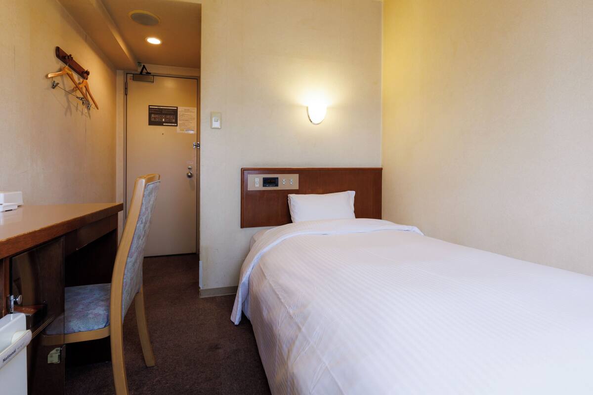 A hotel room with a bed, a desk, and a chair.