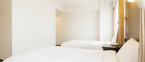 A hotel room with two beds, a bedside table, a lamp, and a ceiling light.