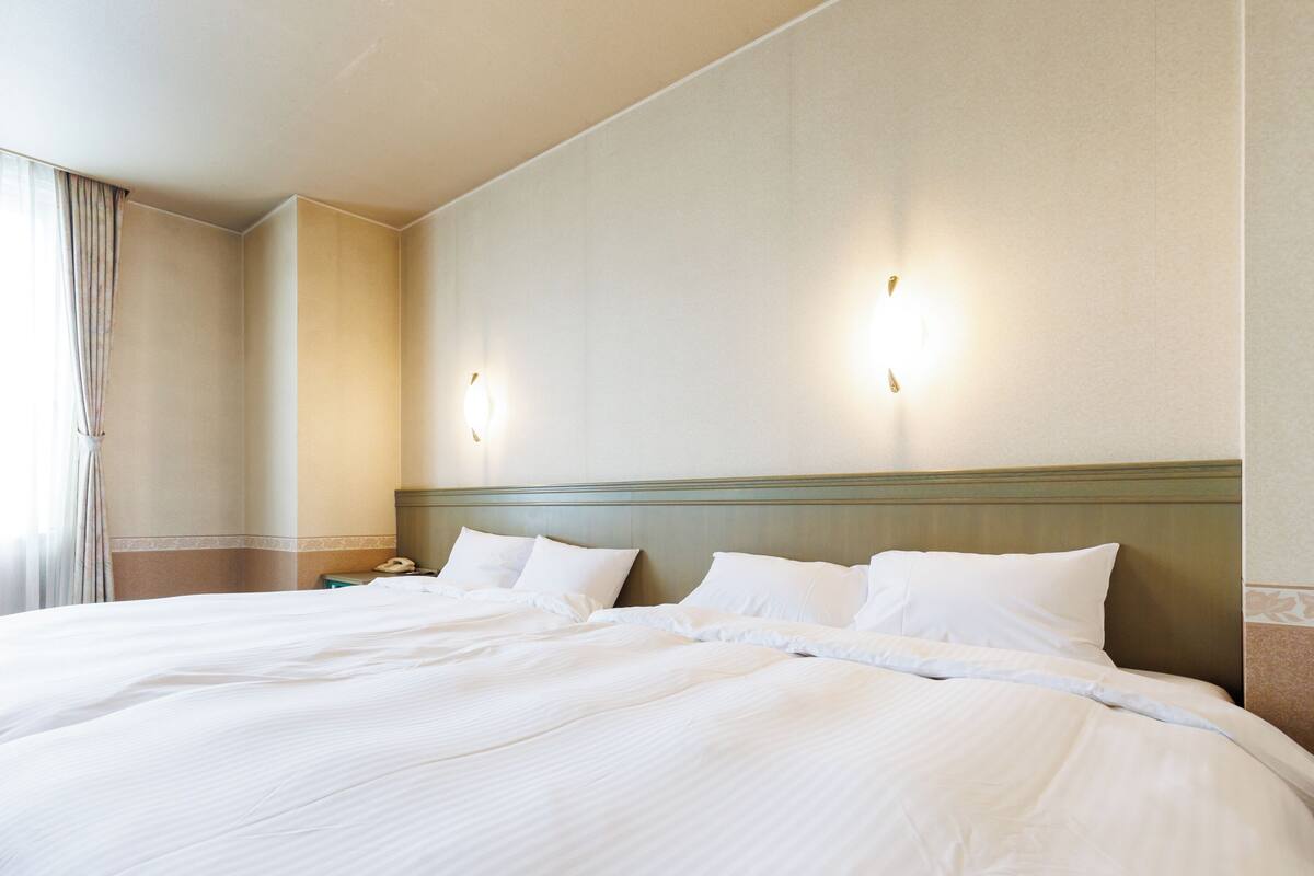 A hotel room with a large bed, two wall-mounted light fixtures, and a nightstand with a phone.