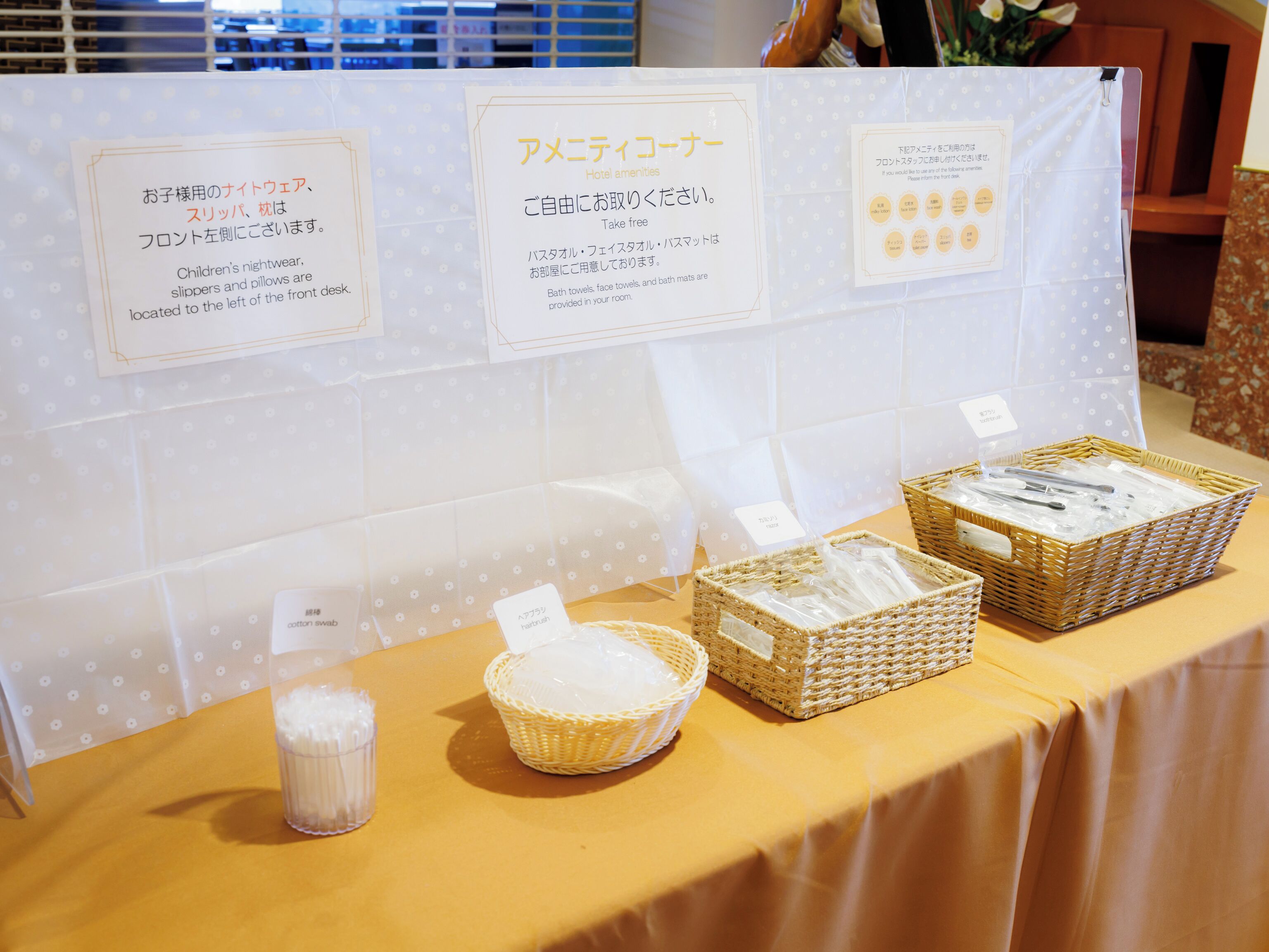 A hotel display table with signs in Japanese detailing amenities like bath towels, face towels, and bath mats.