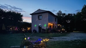 Una casa amb teulada inclinada, un petit porxo i un jardí frontal ben il·luminat amb llumetes.