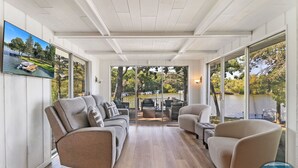 A spacious living area with a large window overlooking a lake, a comfortable sofa, and a chair.