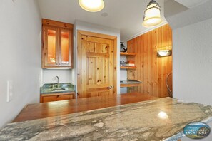 Eine Küche mit Holzschränken, einer Marmorarbeitsplatte und einer Holzwandverkleidung.