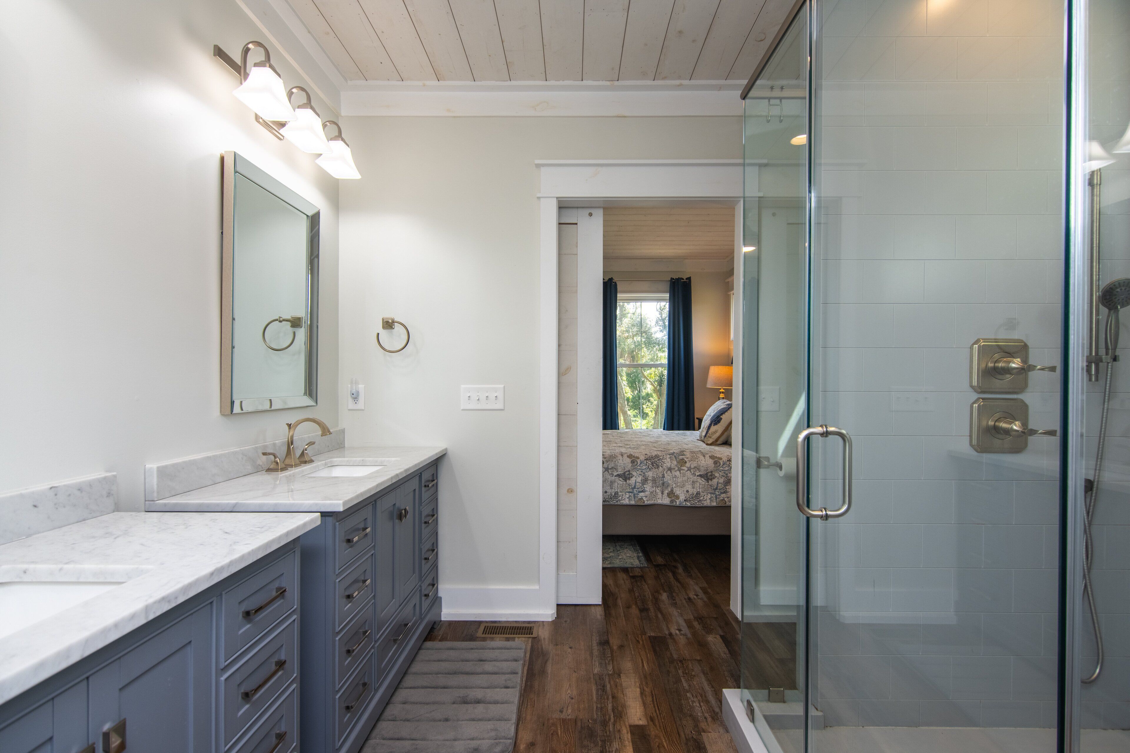 A bathroom with a glass shower enclosure, a double sink vanity, and a large mirror.
