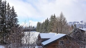 Una cabaña de madera rodeada de árboles nevados y un paisaje montañoso.