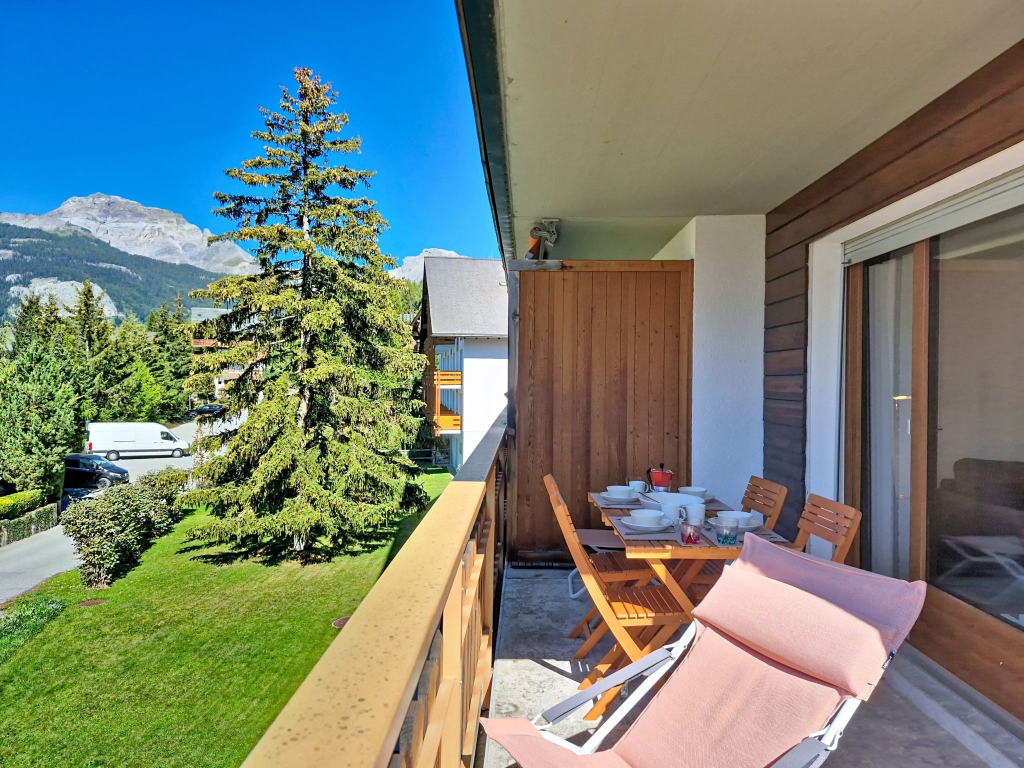 A balcony with a table set for dining, overlooking a mountain and a forested area.
