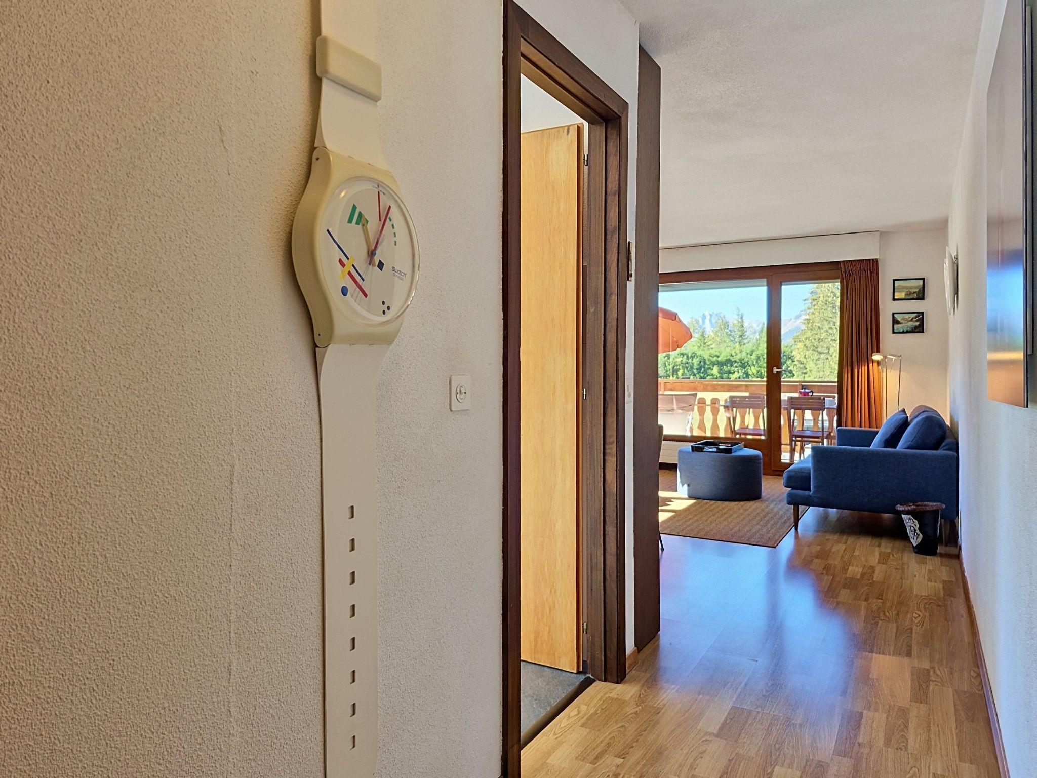 A hallway leading to a balcony with a sofa and a table.