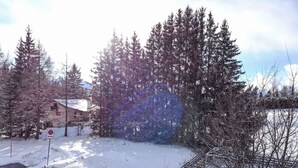 Un paisaje cubierto de nieve con un edificio, árboles y una vía de tren.