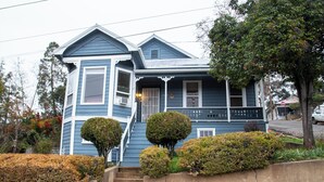 A two-story house with a porch, a front door, and a staircase leading to the entrance. - Historical Victorian with Modern Touch. Garage with EV Charger (Sonora)
