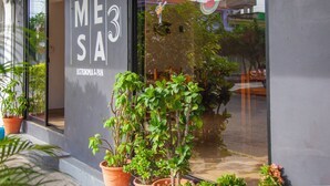 A storefront with the name "MESA" and a sign indicating it is a bistro and pan establishment. There are potted plants in front of the entrance. - Hotel del profe (Santa María Huatulco)