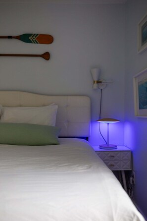 Un lit avec des oreillers, une pagaie accrochée au mur, une lampe de chevet et un tableau encadré.