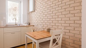 A kitchen with white cabinets, a wooden table, and a brick wall.