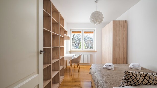 A bedroom with a bed, a desk, and a wardrobe.