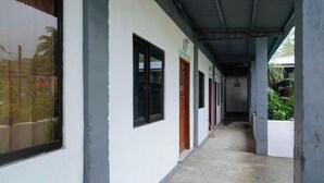 A corridor with white walls and black-framed windows, leading to multiple doors. - RedDoorz @ St Anthony Beach Resort (Asturias)