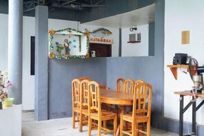 Un comedor con mesa y sillas de madera, pared decorativa y techo con vigas a la vista.