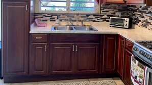 A kitchen with dark wooden cabinets, a double sink, a toaster, and a stove. - Bamboo – New Apt. - Downtown/Sea View - Perfect Location (Charlotte Amalie West)