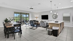 A modern kitchen with a central island, a dining area with a wooden table and chairs, and a living area with a sofa and chairs. - 163KB - Balmoral Resort, a spacious 4-bedroom retreat perfect for families (Haines City)